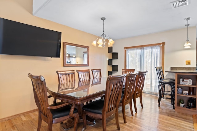 dining room with an inviting chandelier and light hardwood / wood-style flooring