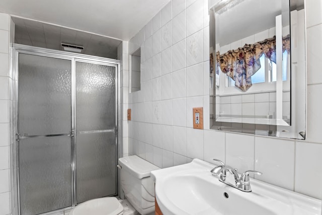 bathroom with toilet, an enclosed shower, sink, and tile walls