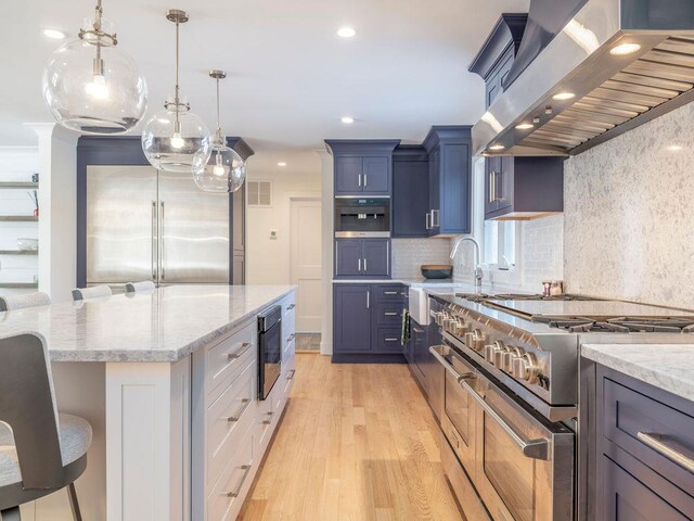 155 Pinewood Rd, Cutchogue, NY 11935 - kitchen featuring recessed lighting, wall chimney exhaust hood, a sink, light wood finished floors, and premium appliances