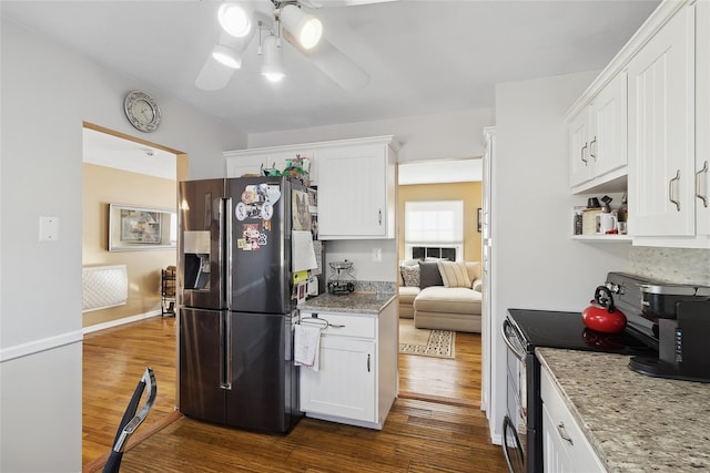 kitchen featuring electric range oven, light stone counters, white cabinets, and black fridge with ice dispenser