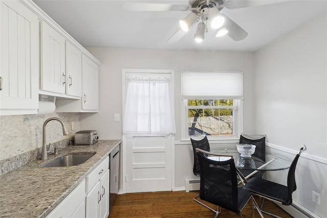 kitchen with a baseboard radiator, sink, white cabinets, backsplash, and light stone countertops