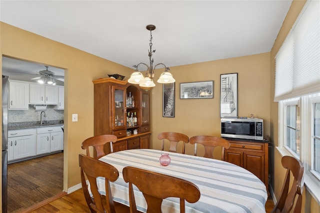 dining room with dark hardwood / wood-style flooring, sink, and ceiling fan with notable chandelier