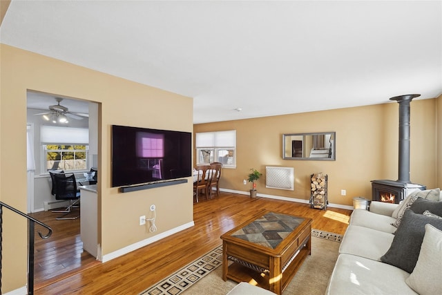 living room featuring wood-type flooring, baseboard heating, and a wood stove