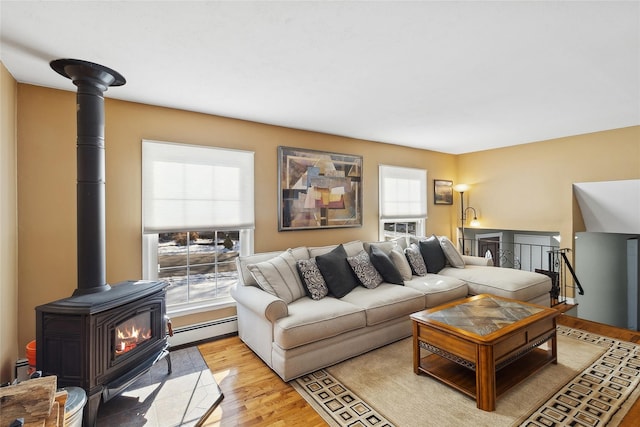 living room with a wood stove, light hardwood / wood-style floors, and baseboard heating