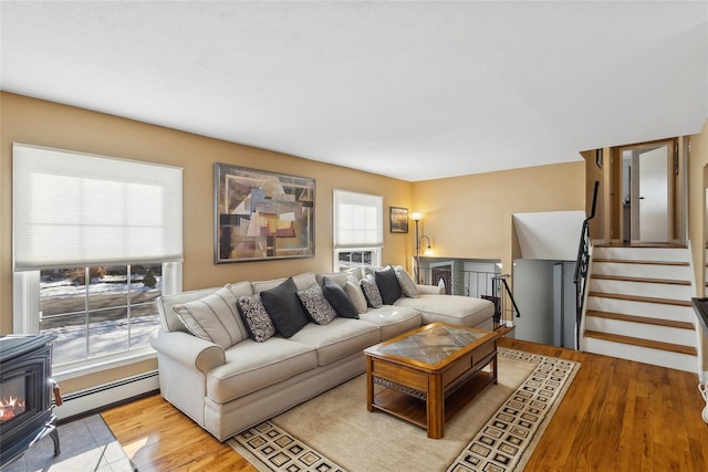 living room featuring baseboard heating, light hardwood / wood-style flooring, and a wood stove