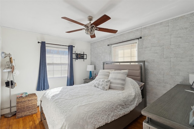 bedroom with multiple windows, dark hardwood / wood-style flooring, a baseboard radiator, and ceiling fan