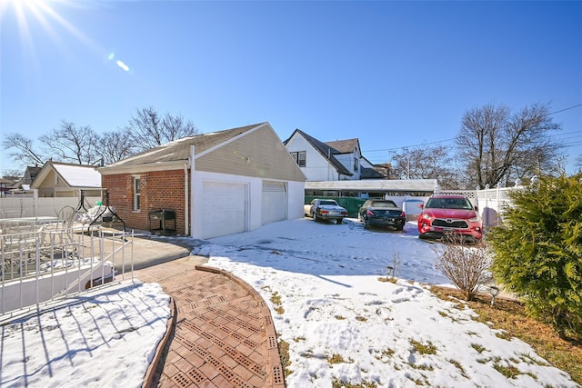 view of snow covered exterior featuring a garage and an outdoor structure