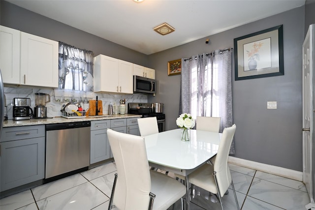 kitchen featuring gray cabinets, white cabinets, backsplash, stainless steel appliances, and a healthy amount of sunlight