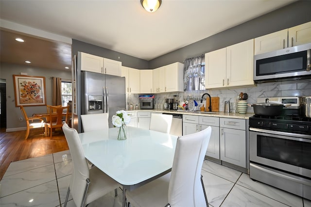 kitchen featuring sink, a center island, stainless steel appliances, decorative backsplash, and white cabinets