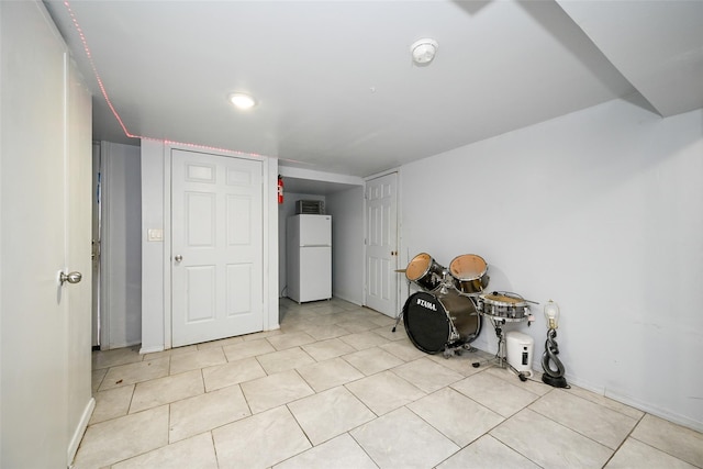 basement featuring light tile patterned flooring and white fridge