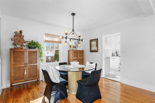 dining space featuring a notable chandelier, sink, and light wood-type flooring