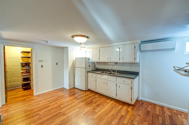 kitchen featuring an AC wall unit, sink, white fridge, and white cabinets