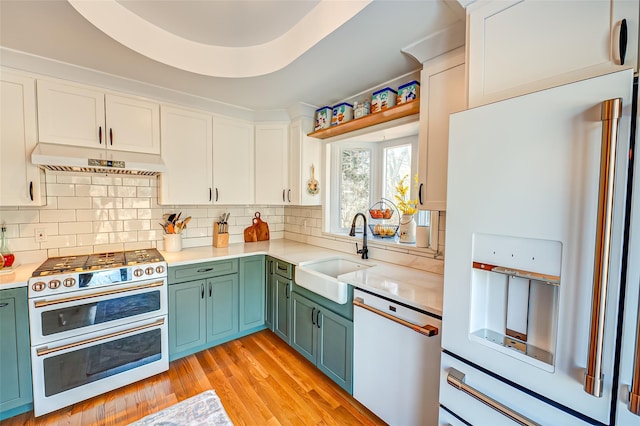 kitchen featuring sink, white cabinetry, dishwasher, white refrigerator with ice dispenser, and range with two ovens