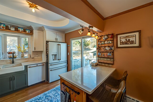 kitchen with sink, crown molding, dishwasher, white cabinetry, and high quality fridge