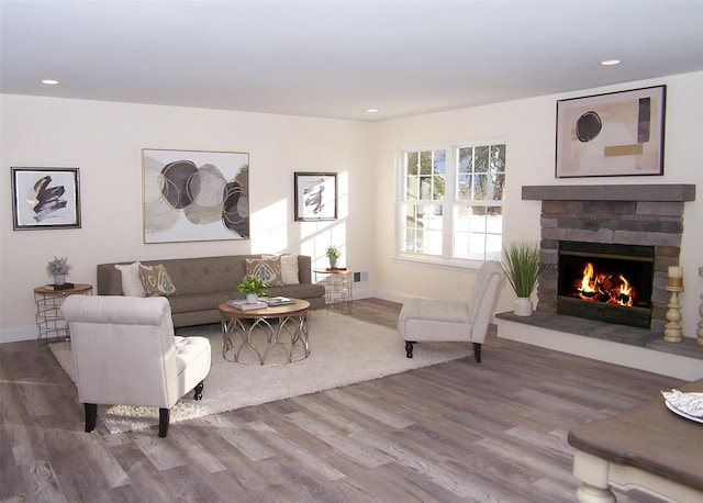 living room featuring a stone fireplace and hardwood / wood-style floors