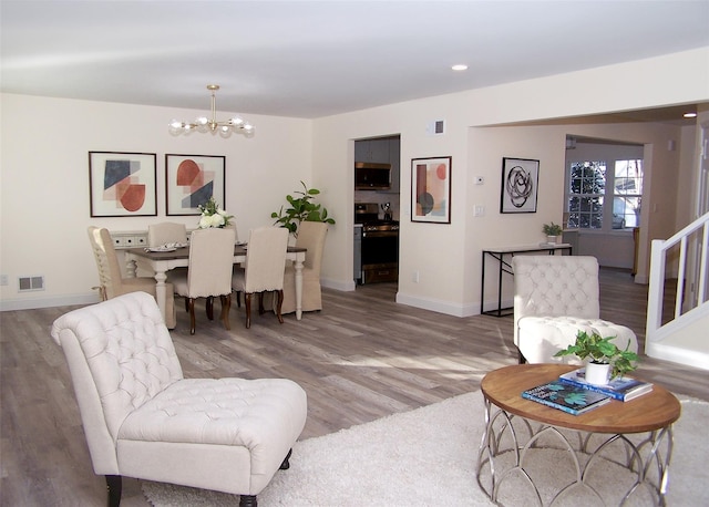 living room with an inviting chandelier and light hardwood / wood-style flooring