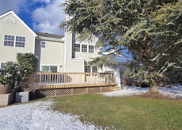 snow covered house with a yard and a deck