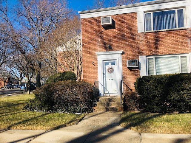 view of front of house with a wall mounted AC and a front lawn