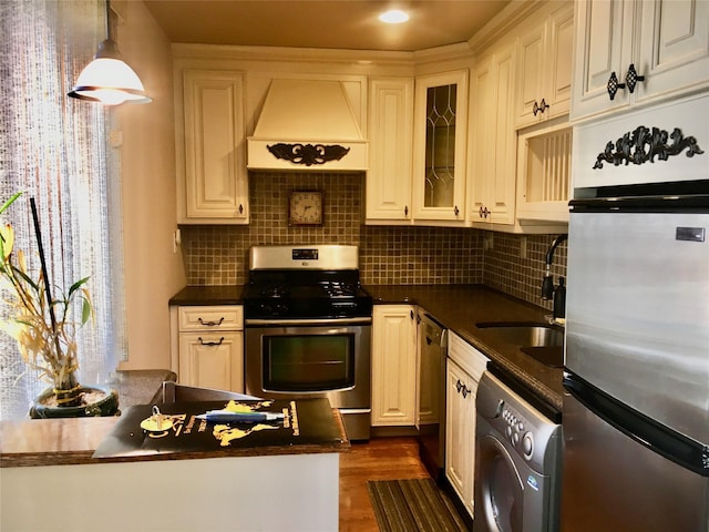 kitchen with sink, stainless steel gas range, refrigerator, washer / dryer, and custom exhaust hood