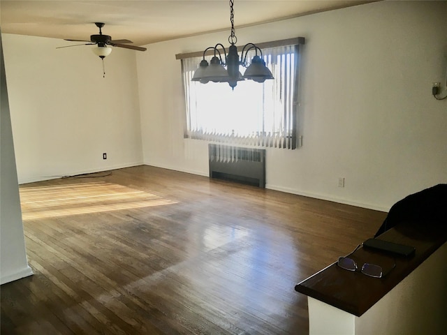 spare room featuring radiator heating unit, dark hardwood / wood-style flooring, and ceiling fan with notable chandelier