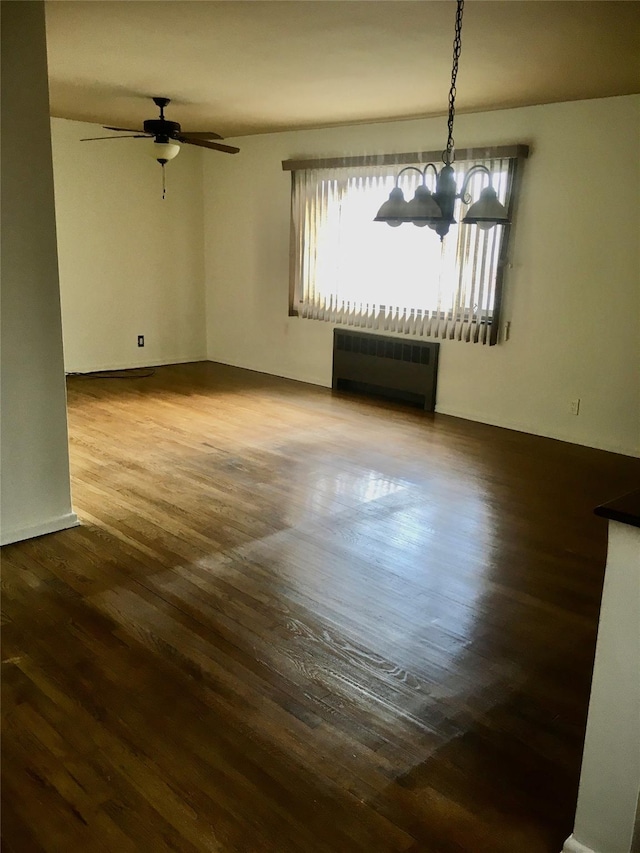 unfurnished room featuring ceiling fan with notable chandelier, radiator, and hardwood / wood-style floors