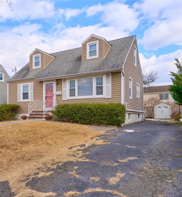 cape cod-style house with a storage unit