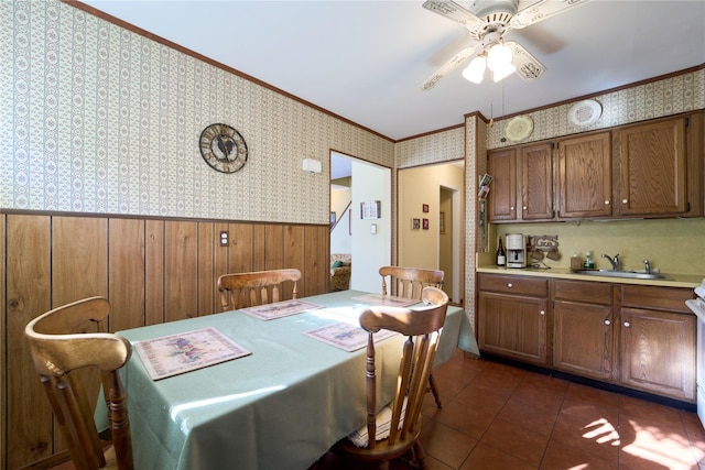 dining space with ceiling fan, ornamental molding, dark tile patterned flooring, and sink