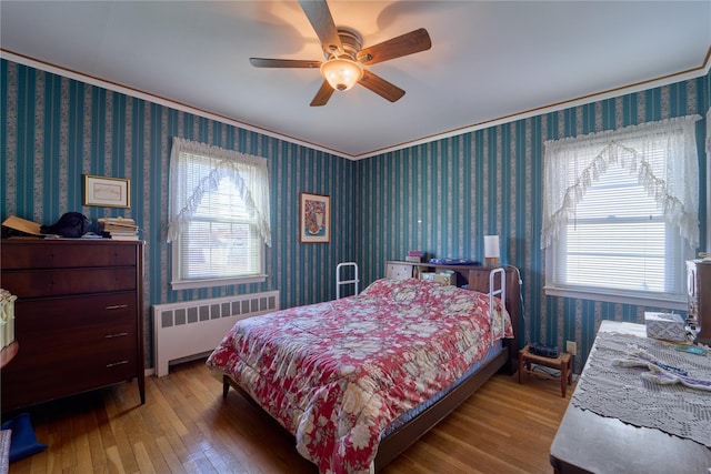 bedroom with hardwood / wood-style flooring, ornamental molding, radiator heating unit, and ceiling fan