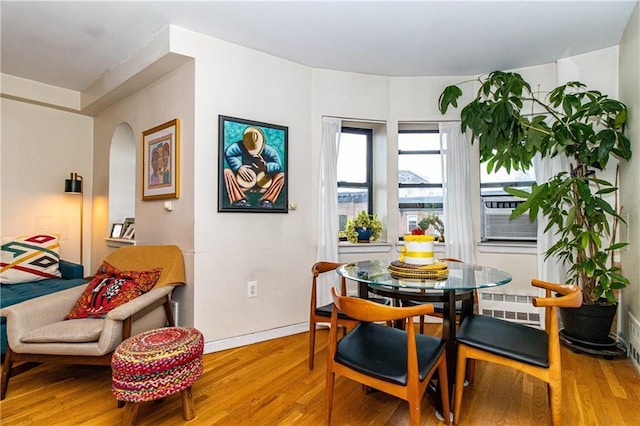 dining space with hardwood / wood-style flooring, radiator, and cooling unit