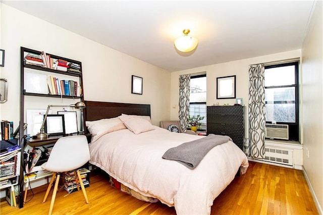 bedroom featuring cooling unit, hardwood / wood-style flooring, and radiator heating unit