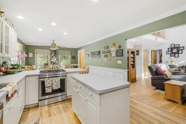 kitchen featuring crown molding, a center island, high end stainless steel range oven, ceiling fan, and white cabinets