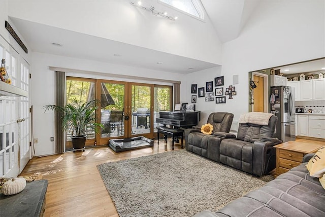 living room featuring french doors, high vaulted ceiling, and light wood-type flooring