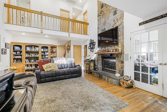 living room featuring hardwood / wood-style floors, a towering ceiling, and a fireplace