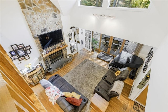 living room featuring hardwood / wood-style flooring, a high ceiling, a fireplace, and french doors