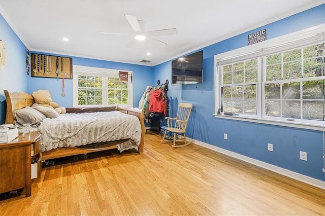 bedroom featuring multiple windows, ornamental molding, ceiling fan, and light wood-type flooring