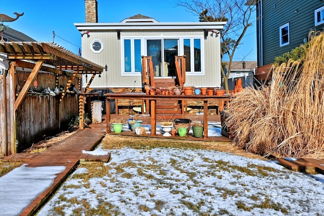 snow covered house featuring a pergola and a deck