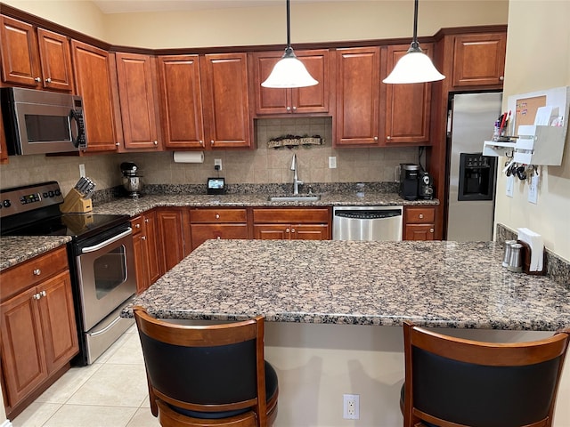 kitchen with appliances with stainless steel finishes, sink, dark stone countertops, and decorative light fixtures