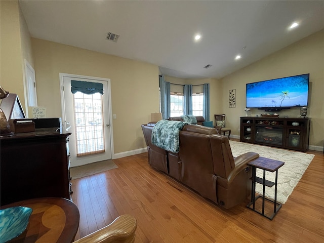 living room with plenty of natural light, vaulted ceiling, and light wood-type flooring