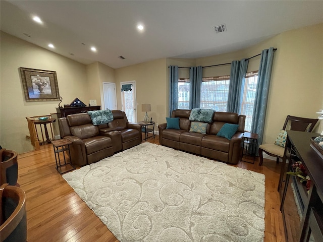 living room featuring lofted ceiling and light hardwood / wood-style floors