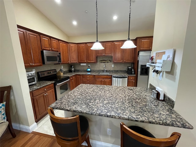 kitchen featuring appliances with stainless steel finishes, decorative light fixtures, a breakfast bar, and kitchen peninsula