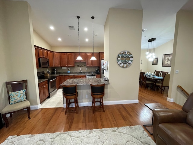 kitchen featuring hanging light fixtures, a breakfast bar area, stainless steel appliances, and light hardwood / wood-style floors