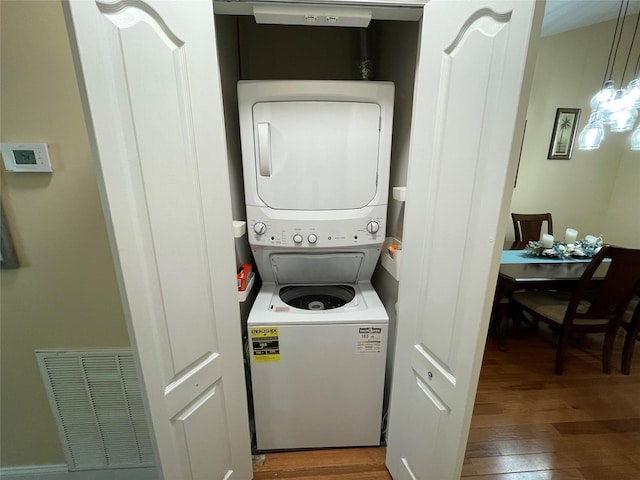 washroom featuring dark hardwood / wood-style flooring and stacked washer and dryer