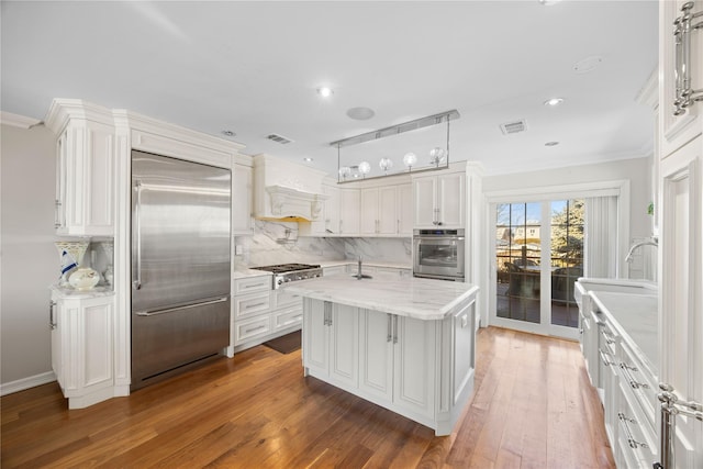 kitchen featuring pendant lighting, appliances with stainless steel finishes, white cabinetry, a center island, and decorative backsplash