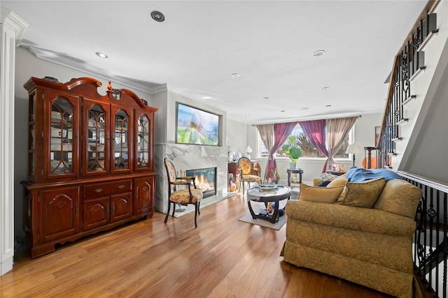 living room featuring a premium fireplace, crown molding, and light hardwood / wood-style floors