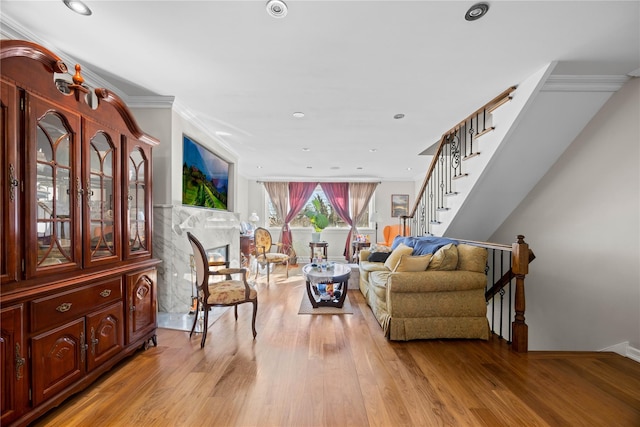 living room with ornamental molding, a high end fireplace, and light hardwood / wood-style floors