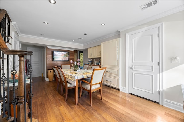 dining area with ornamental molding and light hardwood / wood-style floors