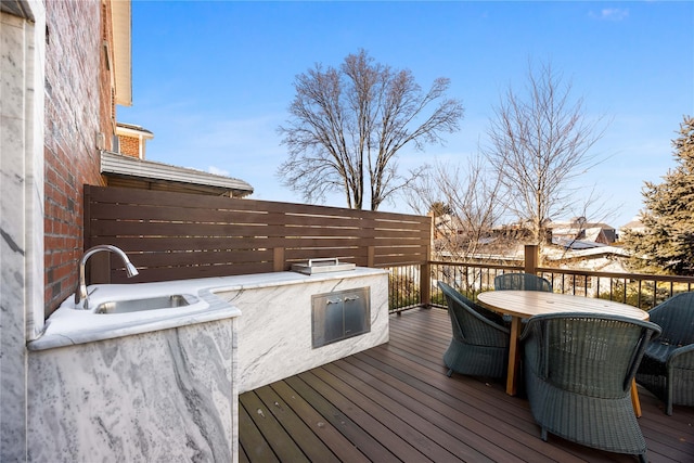 wooden terrace featuring area for grilling and sink