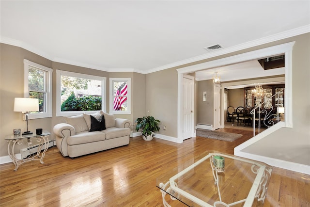 living room with hardwood / wood-style flooring, crown molding, a chandelier, and a baseboard heating unit