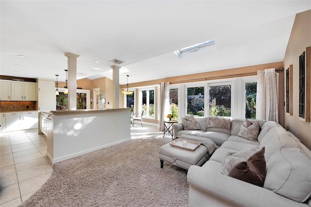 living room with decorative columns, vaulted ceiling, and light tile patterned floors