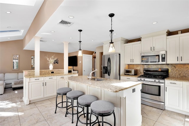 kitchen with appliances with stainless steel finishes, pendant lighting, sink, decorative backsplash, and a center island with sink